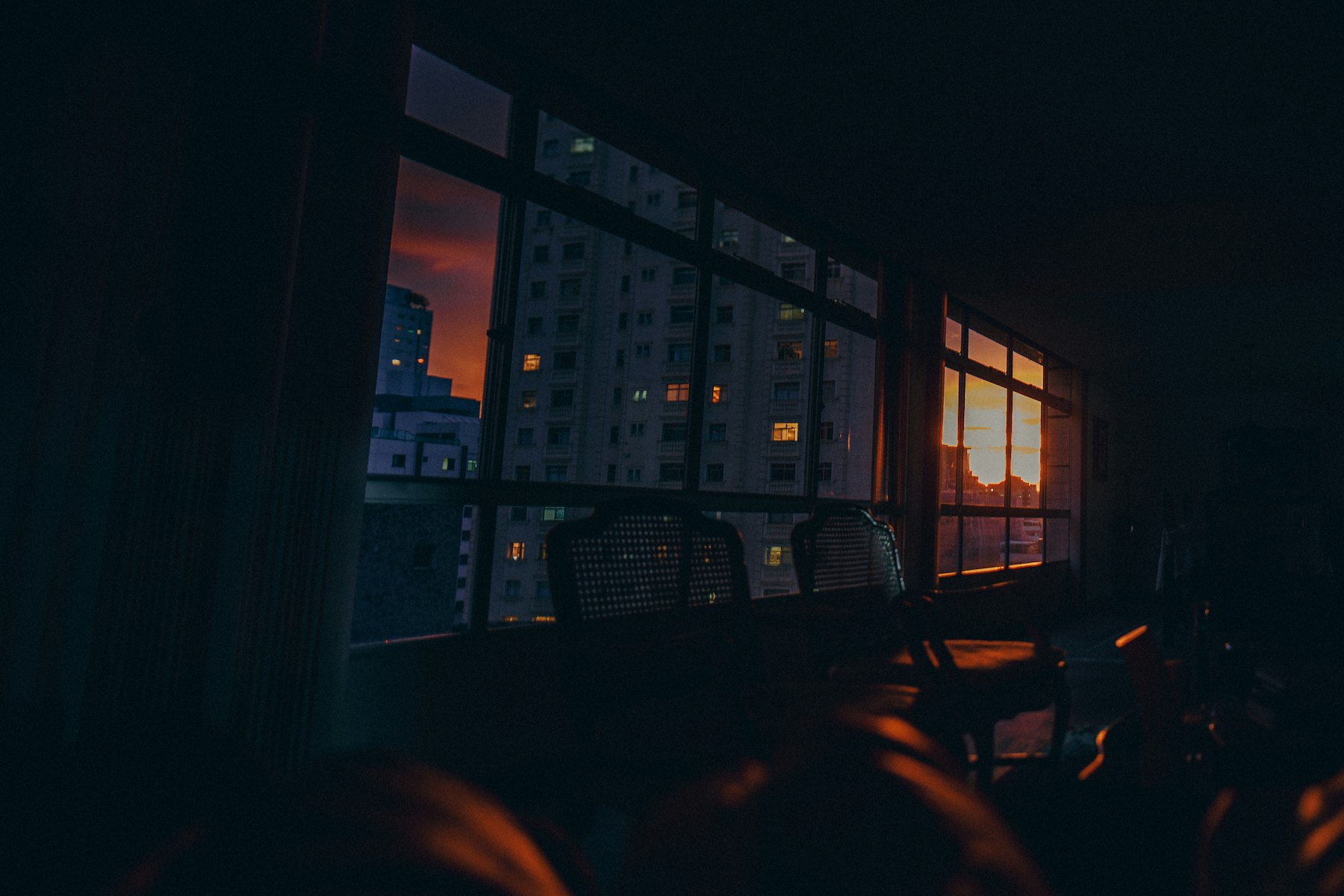 Immeubles de la ville aperçus à travers une fenêtre au coucher du soleil, un dimanche soir