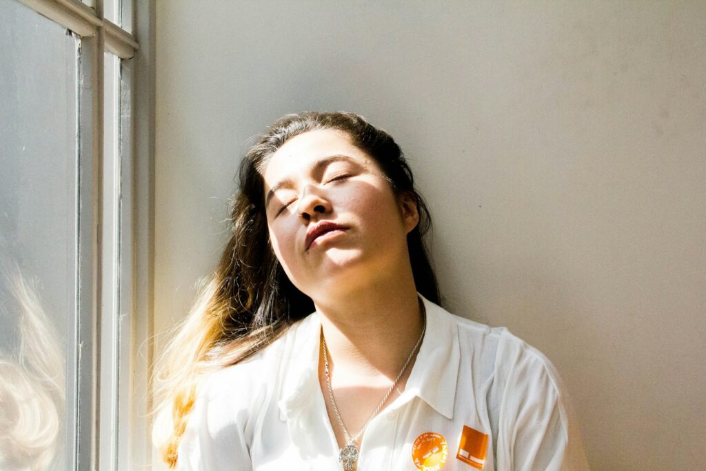 Femme debout près d'une fenêtre lumineuse, prenant une pause pour se détendre