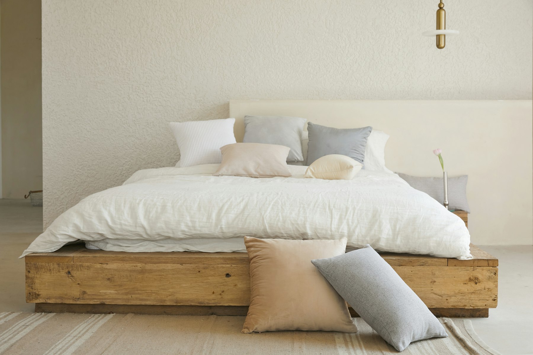 Chambre sobre aux tons clairs avec un lit en bois simple et un oreiller blanc