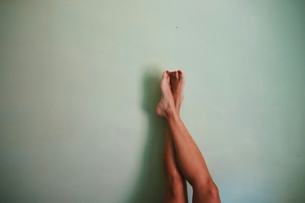 Jambes relevées et pieds nus posés contre un mur clair pour détendre les mollets