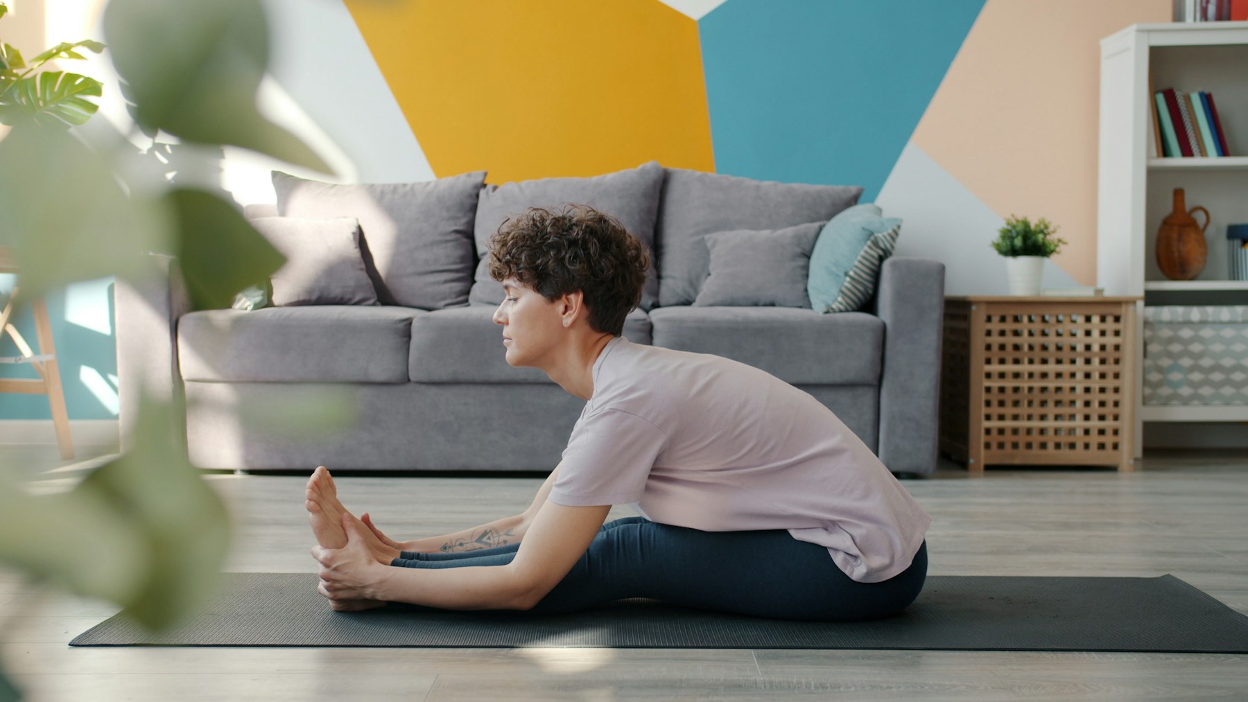Femme assise sur un tapis qui s'étire vers ses jambes dans un salon chaleureux