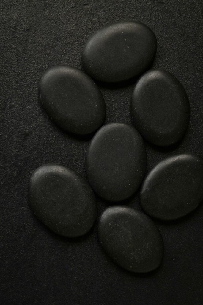 Petits galets de basalte noirs alignés, utilisés pour les soins aux pierres chaudes