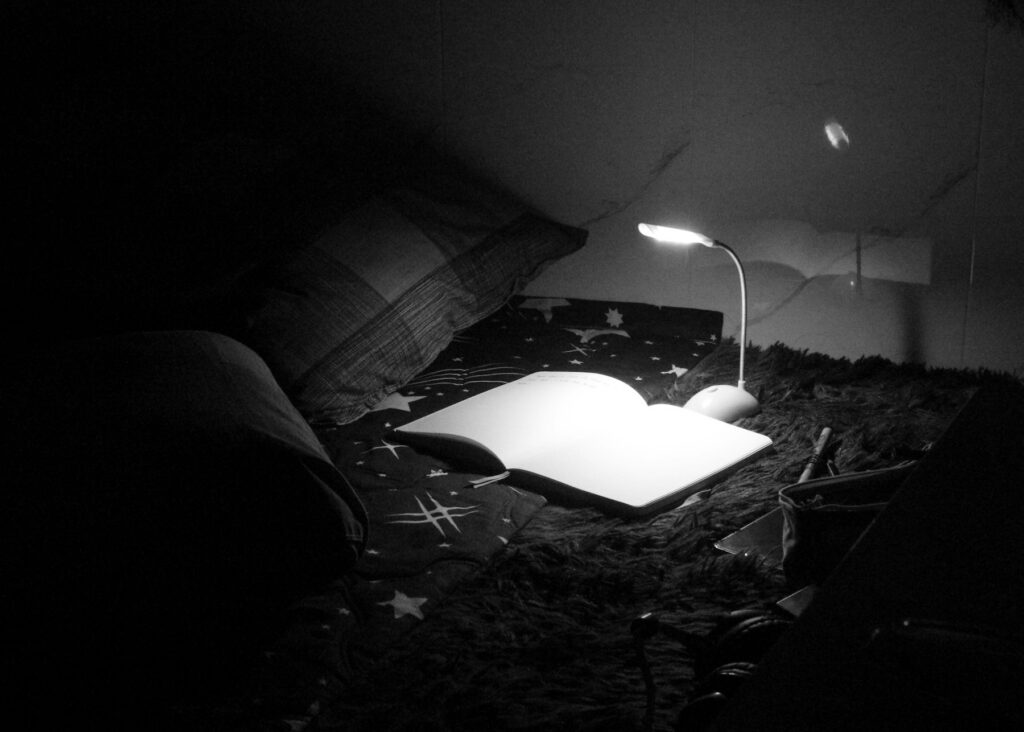 Carnet ouvert éclairé par une petite lampe le soir, prêt à recevoir les pensées du jour