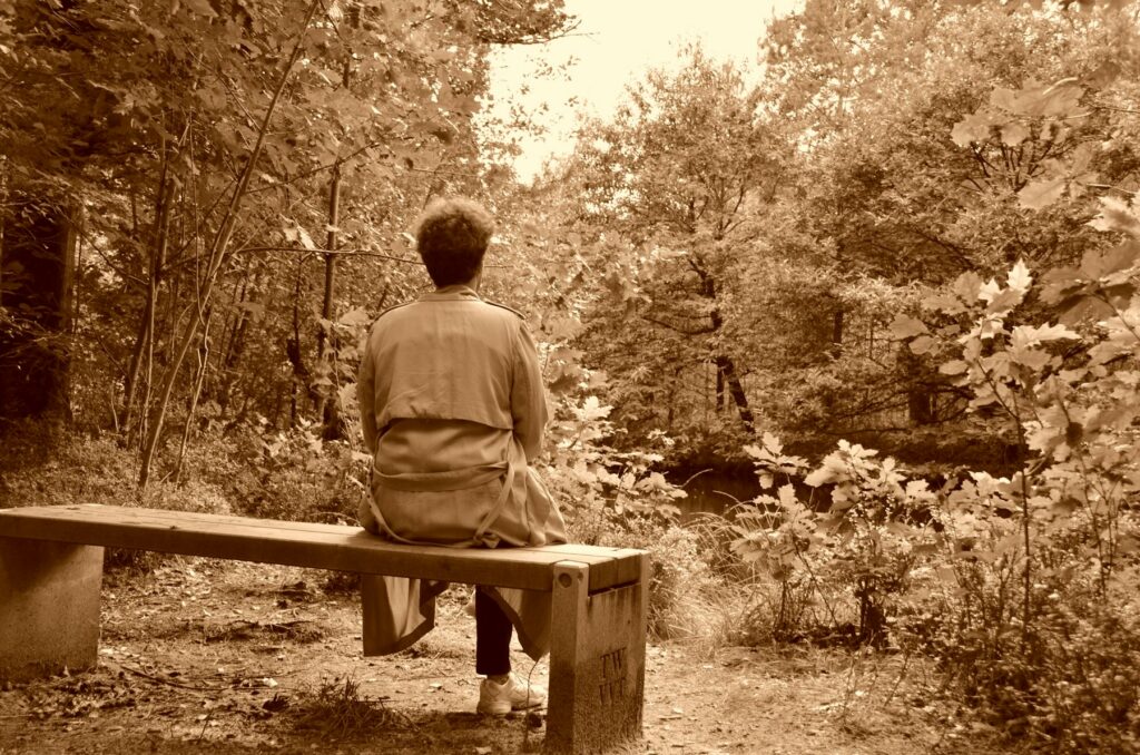 Personne assise sur un banc en forêt, prenant le temps de souffler loin du stress