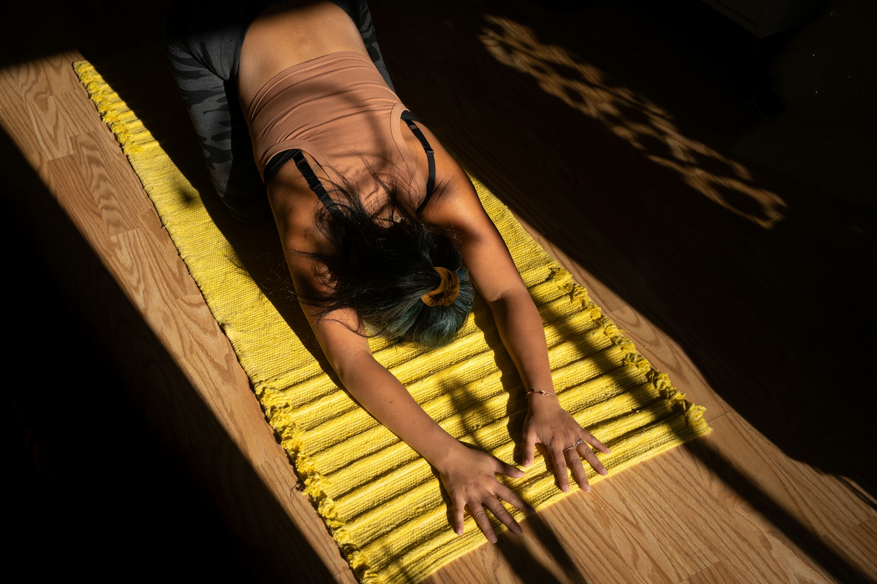 Personne en posture de l'enfant sur un tapis de yoga, le front posé au sol